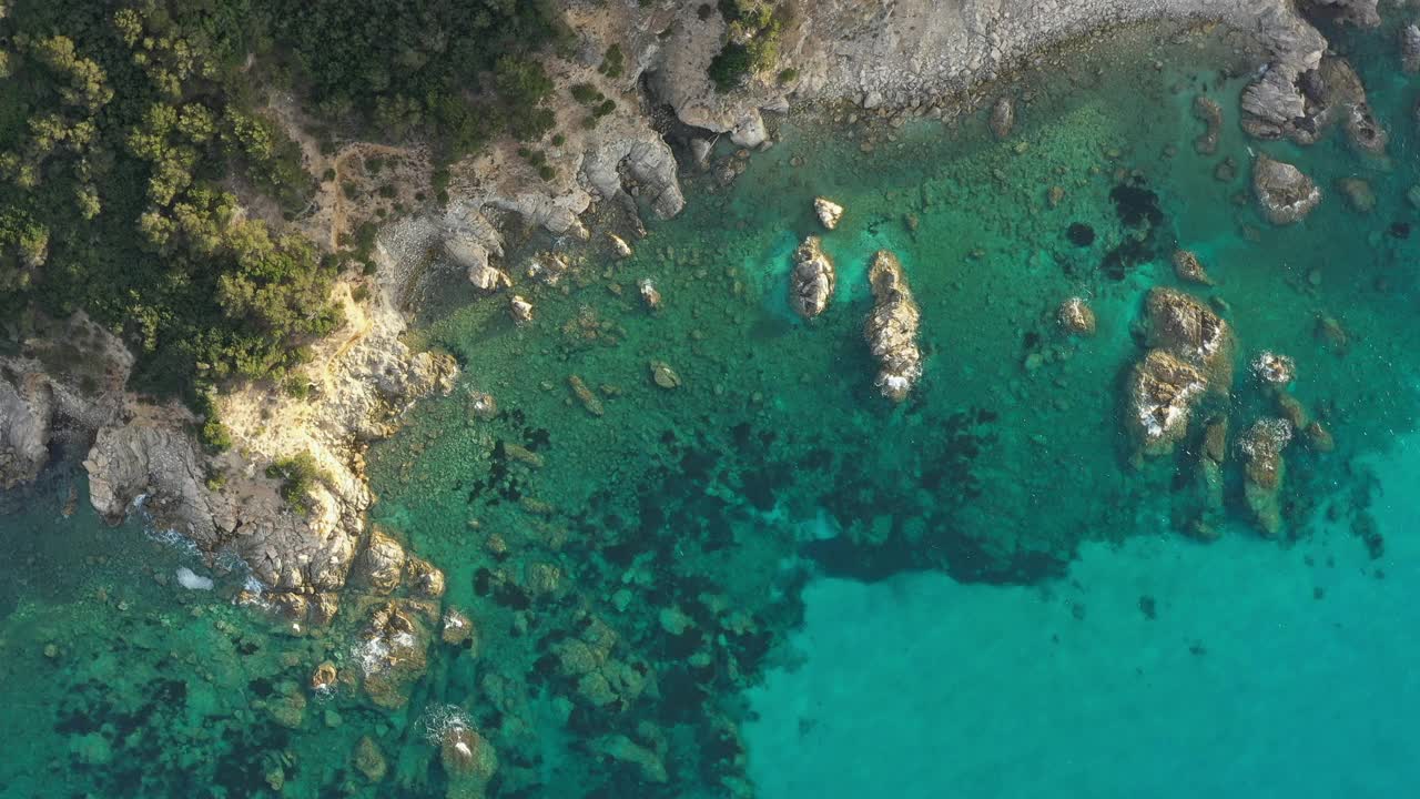 从上面看，令人惊叹的鸟瞰绿色和岩石海岸线沐浴在蓝绿色，水晶般的清澈的水。意大利撒丁岛的翡翠海岸。视频素材