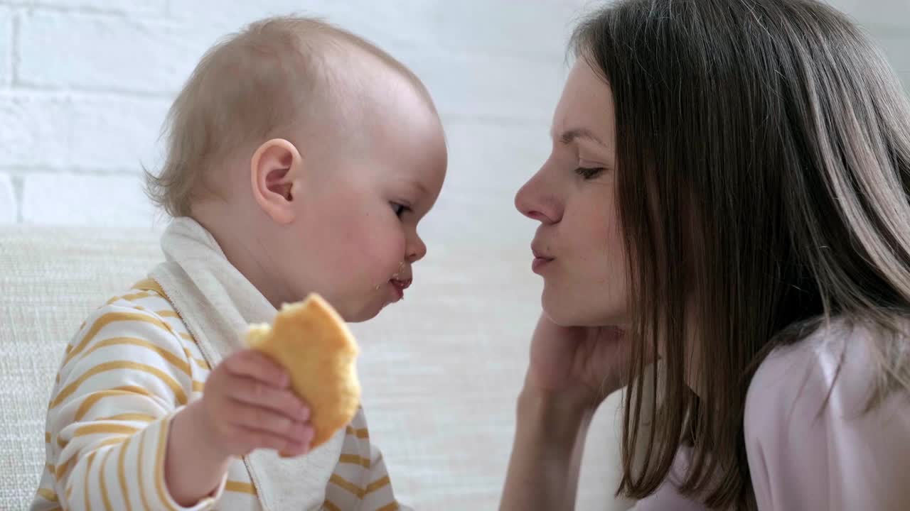 婴儿用又大又好吃的饼干喂妈妈。在家吃婴儿。健康食品，零食或午餐时间视频素材