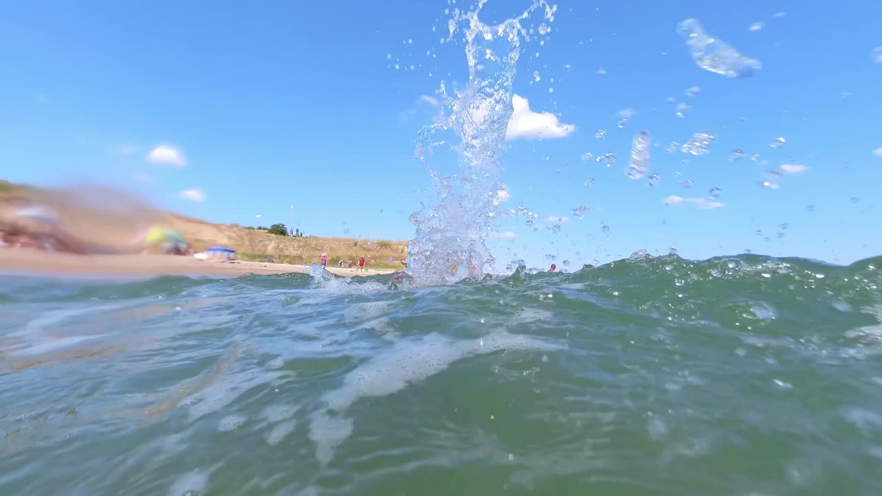 在一个阳光明媚的夏日，一个孩子在大海上游泳，泼水。视频素材