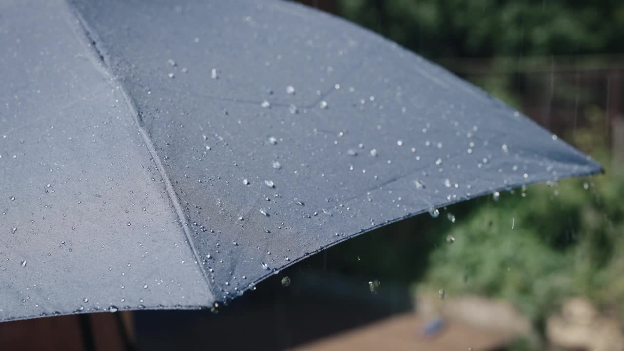 阳光明媚的夏雨。水珠从灰色的伞面上流下来视频素材