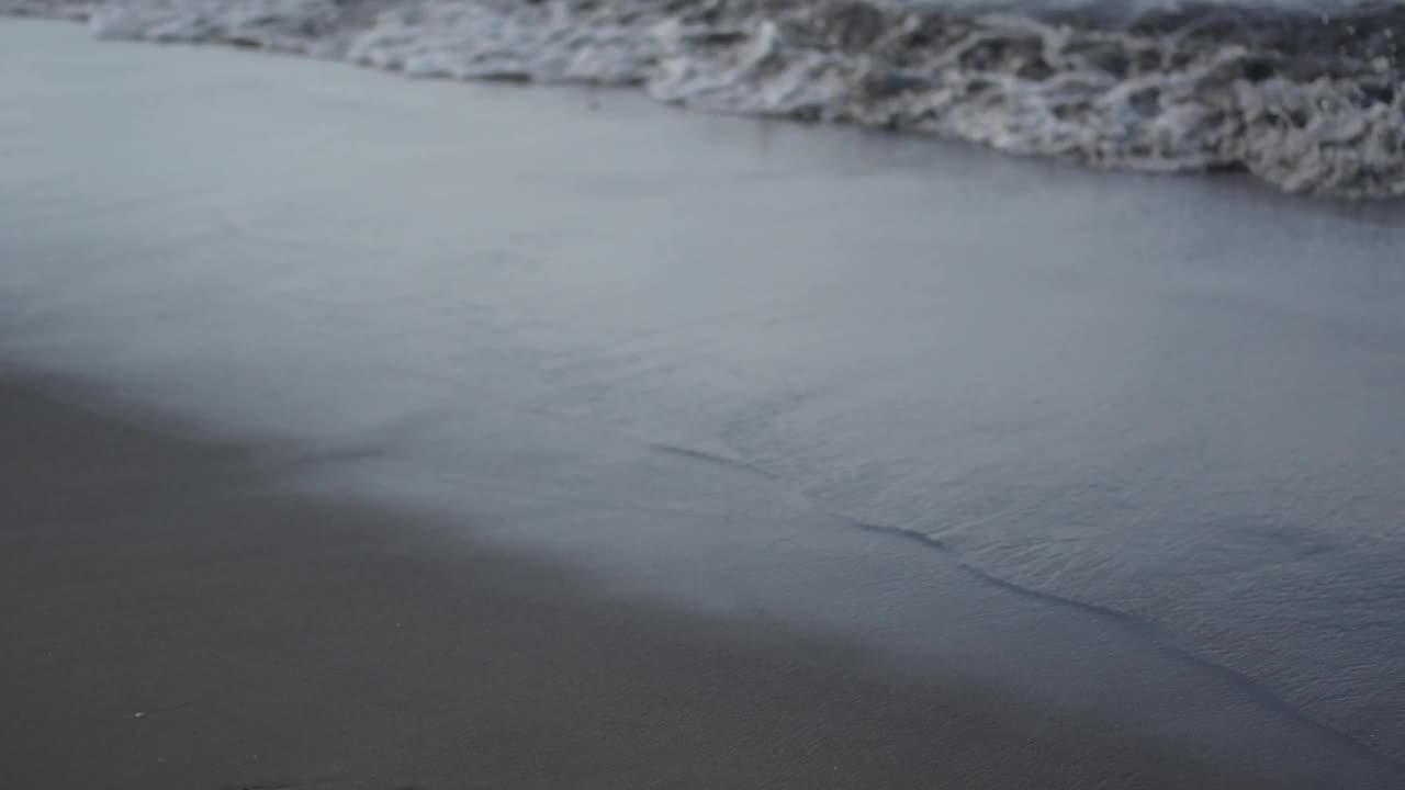 海滩边平静的蓝色海浪，用慢镜头近距离拍摄视频素材