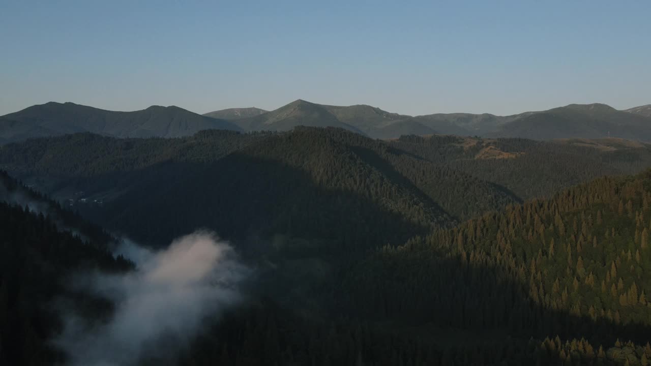 无人机在清晨平静的山顶拍摄了迷人的薄雾。山峰高耸，日出美景自然风光。鼓舞人心的宁静飞行在日出。旅游目的地田园自然概念视频素材