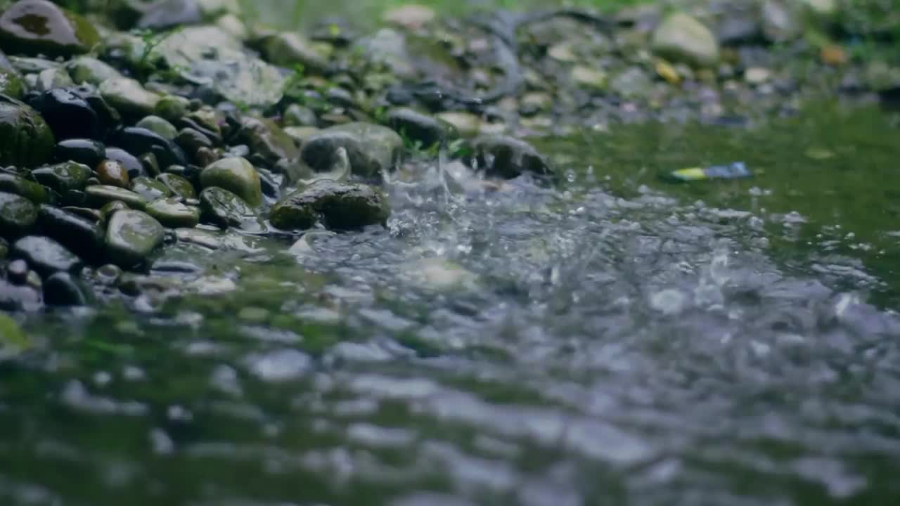 下午下了大雨，雨水落在水坑和小岩石的表面，造成飞溅的倒影视频素材