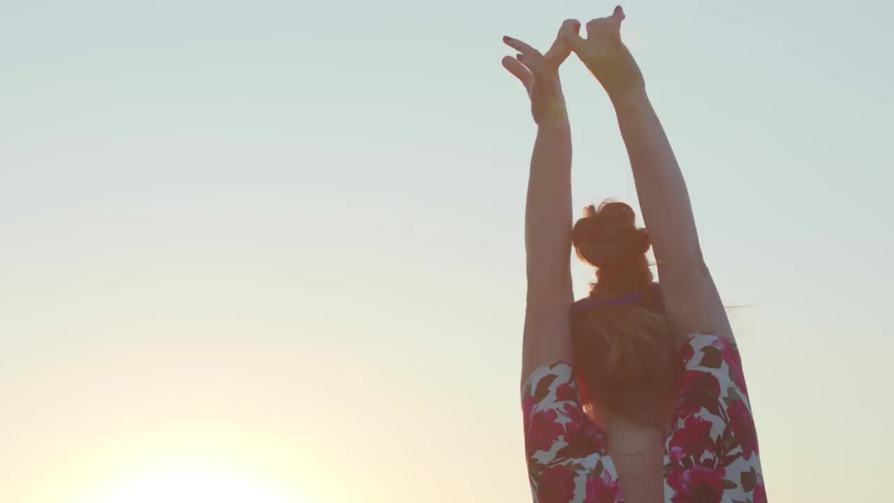 穿着夏装的年轻女子垂下她美丽的长发。夏日的落日照亮了它们。的生活方式。旅行放松。冥想。视频素材