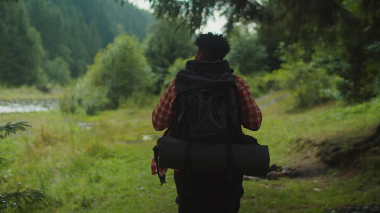 英俊的非洲裔美国人，徒步旅行与背包附近的山河视频素材