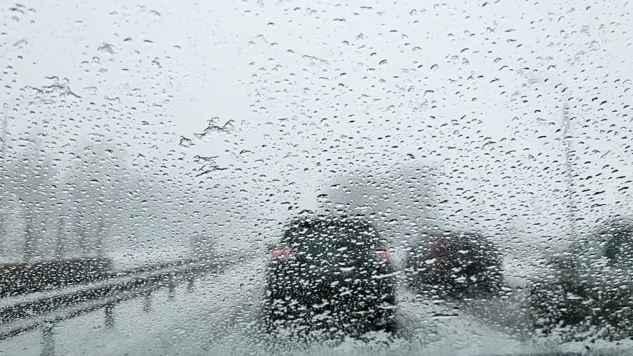 一辆汽车的挡风玻璃上看到融化的雪滴在交通堵塞的路上视频素材