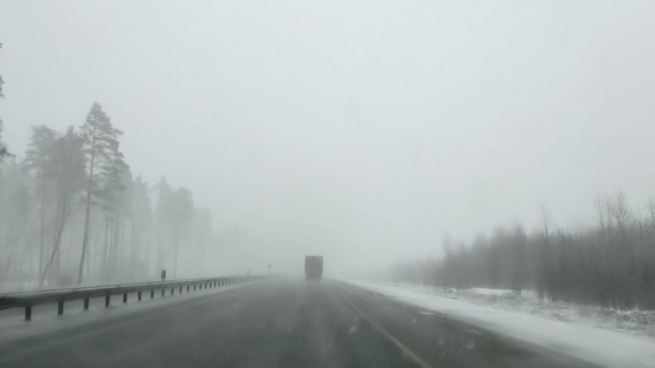 在大雪、能见度低的冬天，通过高速公路上一辆汽车的挡风玻璃看视频素材