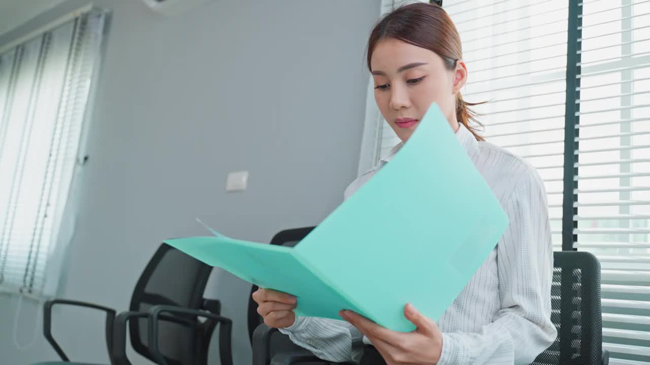 亚洲美女求职者准备在公司面试。有魅力的女性坐在整齐的椅子上，和人事经理紧张地等待申请工作，练习用简历说话视频素材