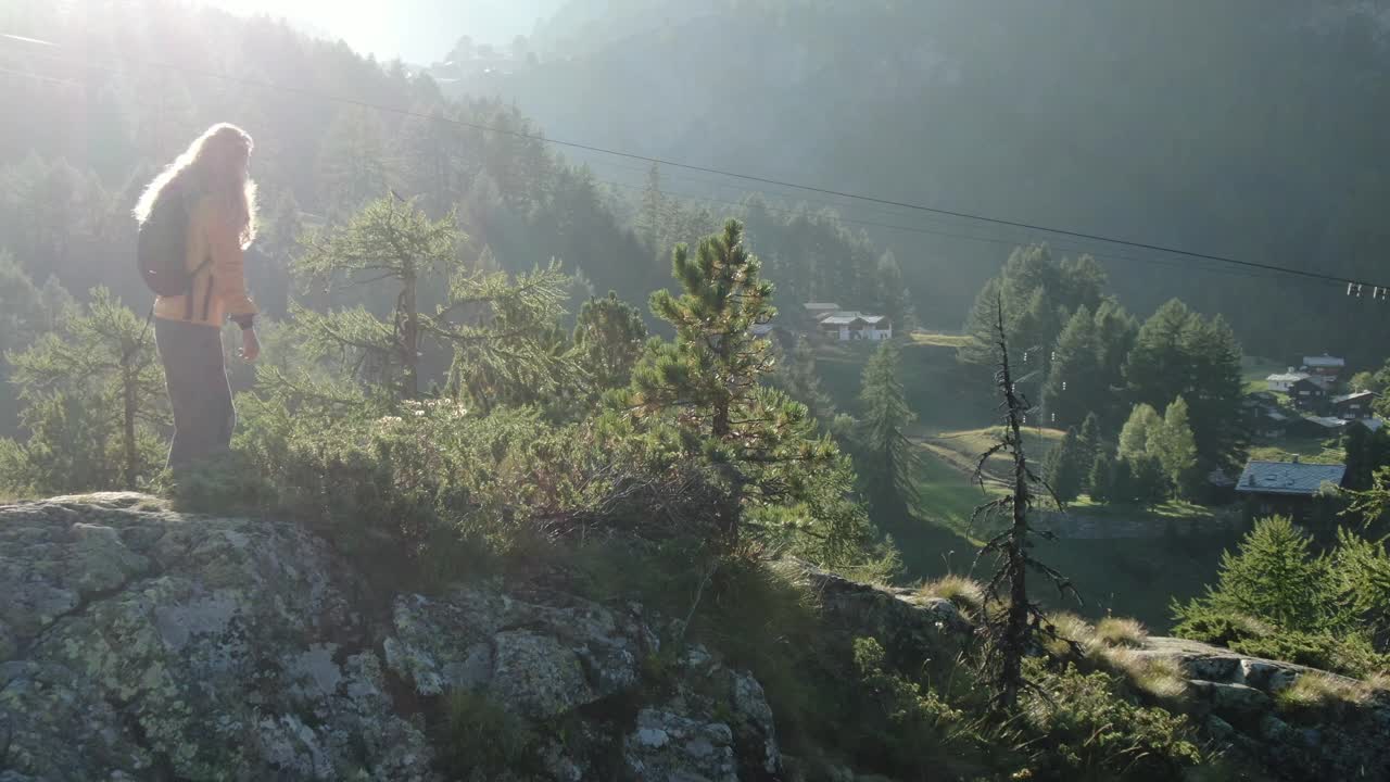 无人机拍摄的一名年轻女性徒步旅行者站在山上露出地表的岩石上视频素材