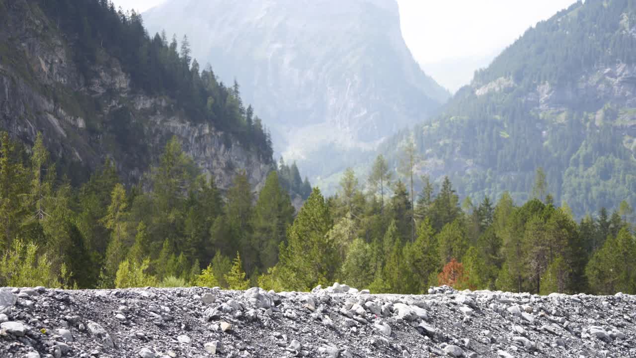 两个徒步旅行者沿着有山和树的岩石地带走着视频素材