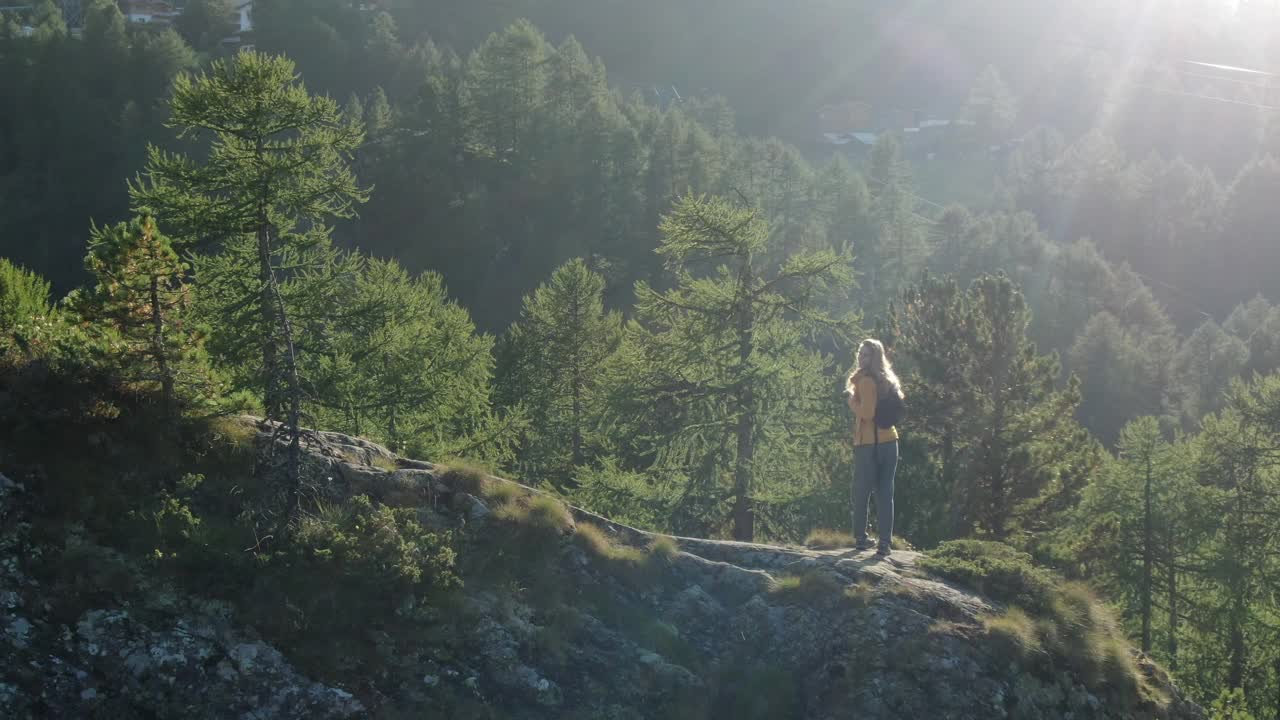 无人机拍摄的一名年轻女性徒步旅行者在山上露出地表的岩石上自由姿势视频素材