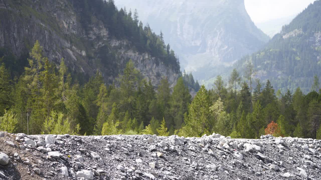 两个徒步旅行者沿着有山和树的岩石地带走着视频素材