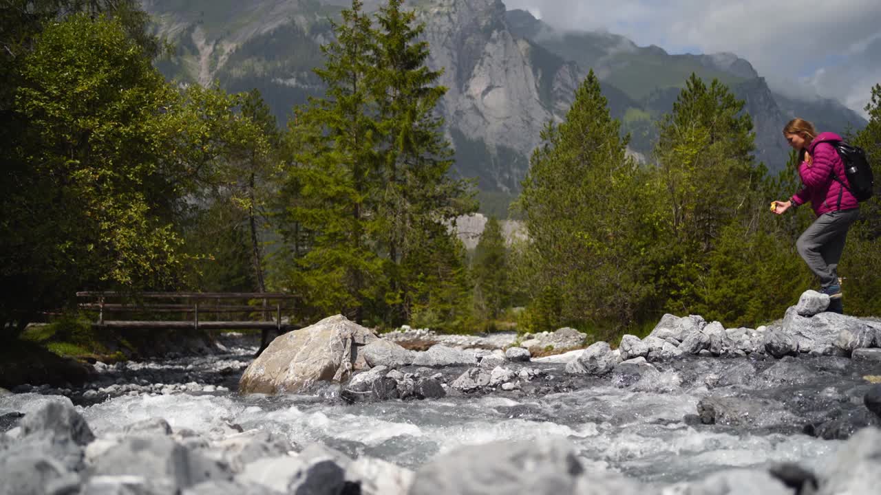 两个徒步旅行者在大岩石上穿过山涧视频素材