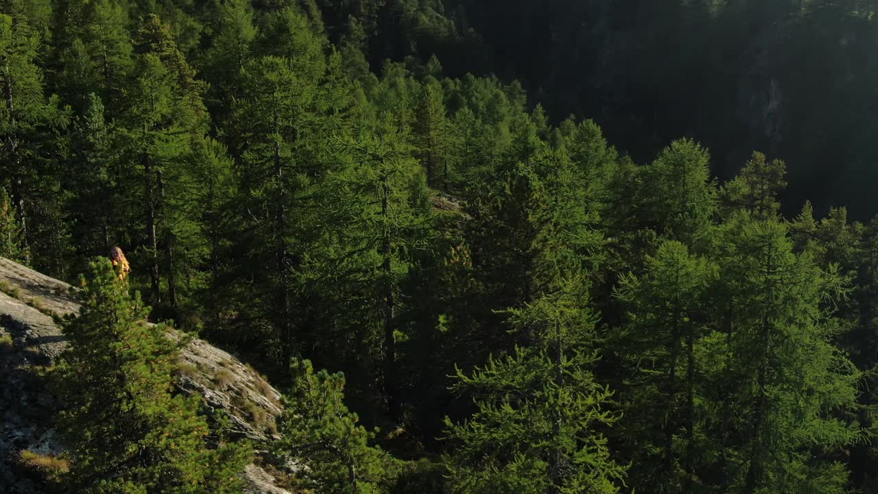 无人机拍摄的一名年轻女性徒步旅行者站在山上露出地表的岩石上视频素材