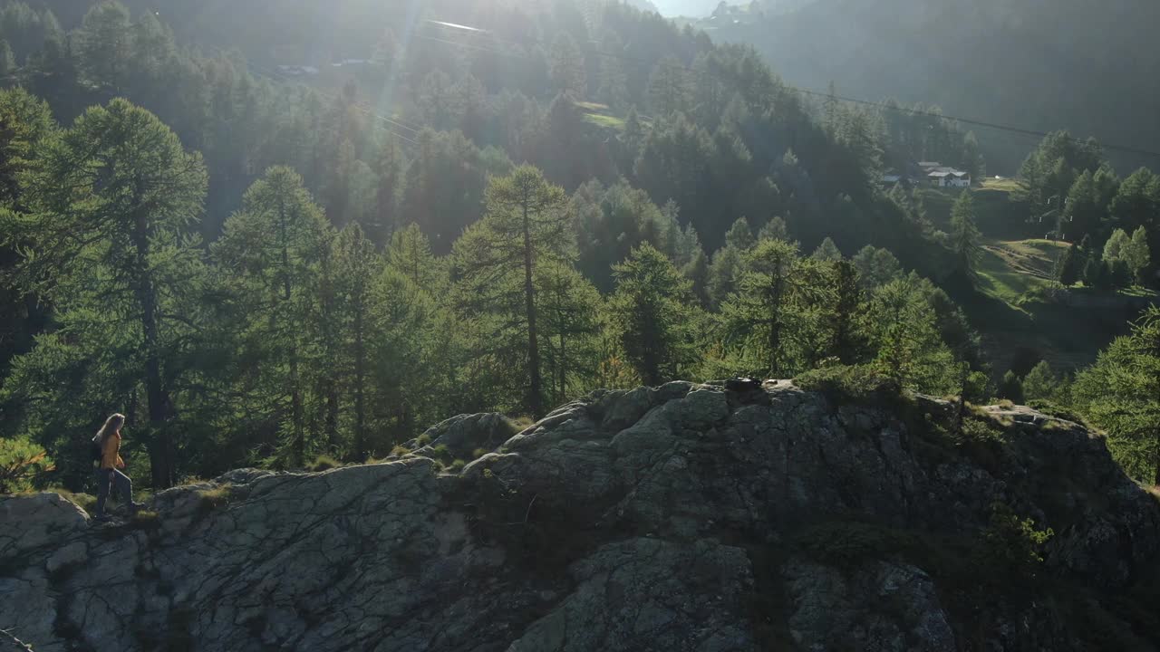 无人机拍摄的一名年轻女性徒步旅行者站在山上露出地表的岩石上视频素材