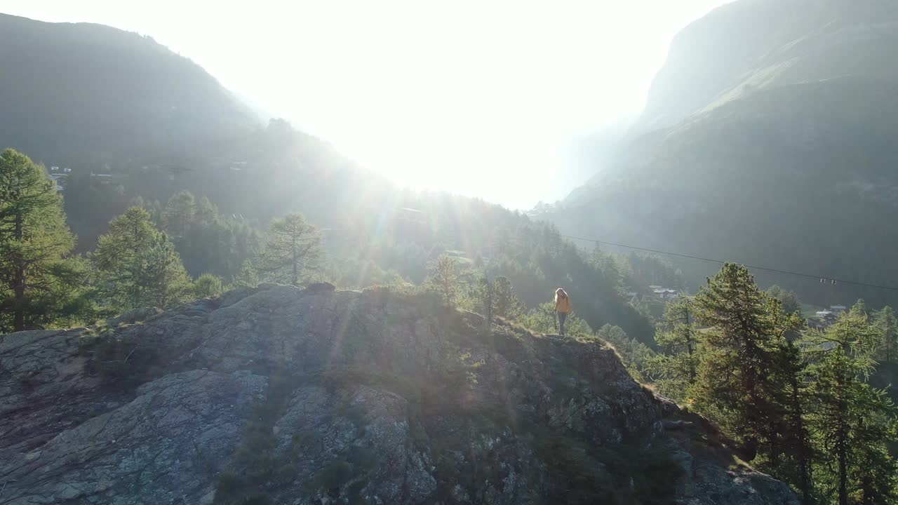 无人机拍摄的一名年轻女性徒步旅行者站在山上露出地表的岩石上视频素材