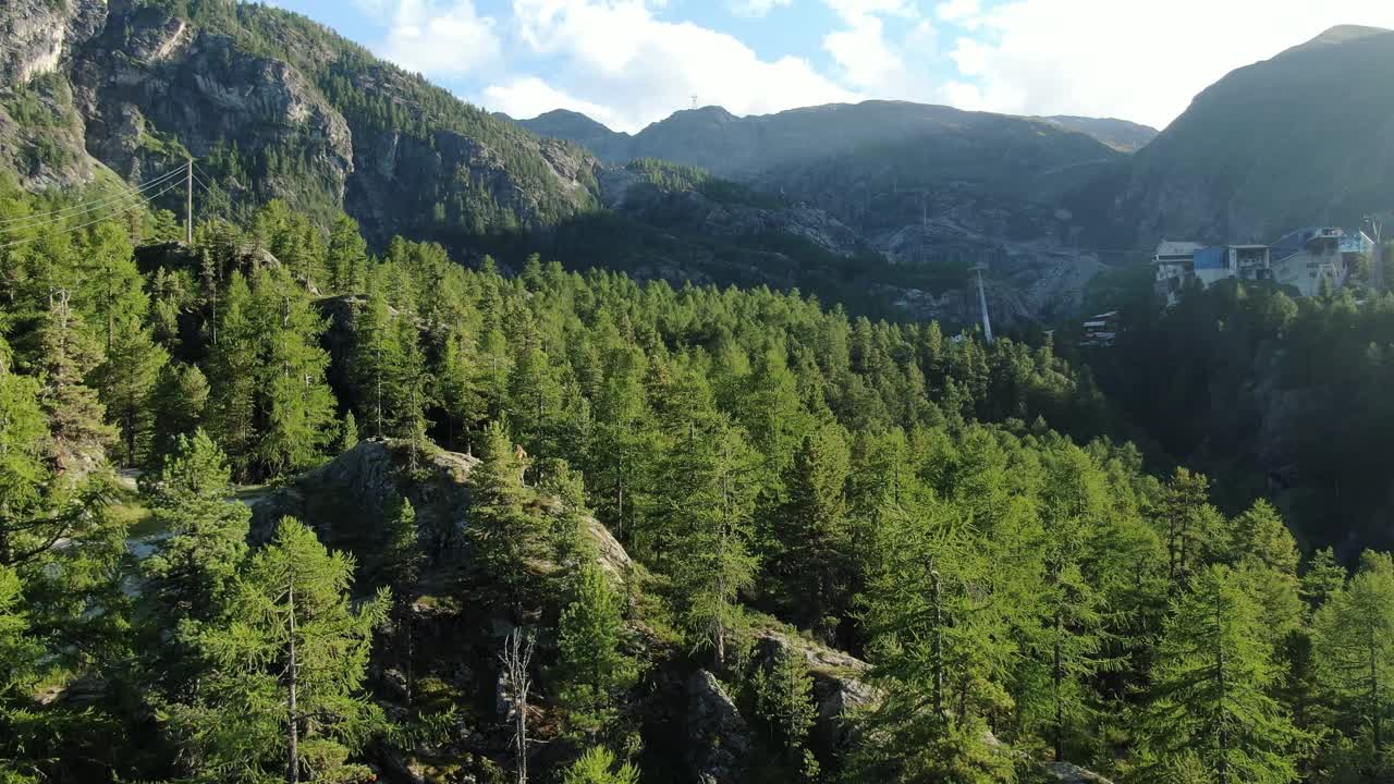 无人机拍摄的一名年轻女性徒步旅行者站在山上露出地表的岩石上视频素材