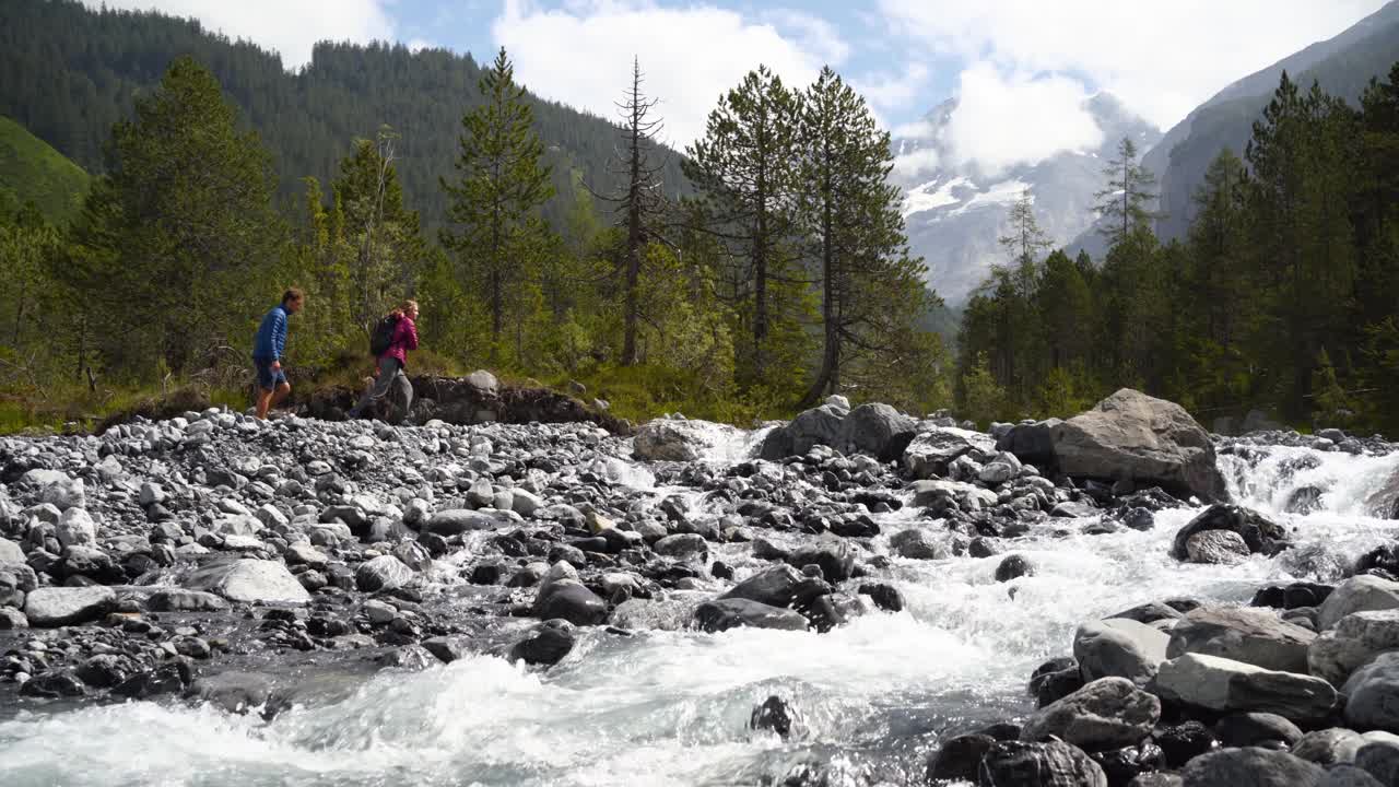 两个徒步旅行者在大岩石上穿过山涧视频素材