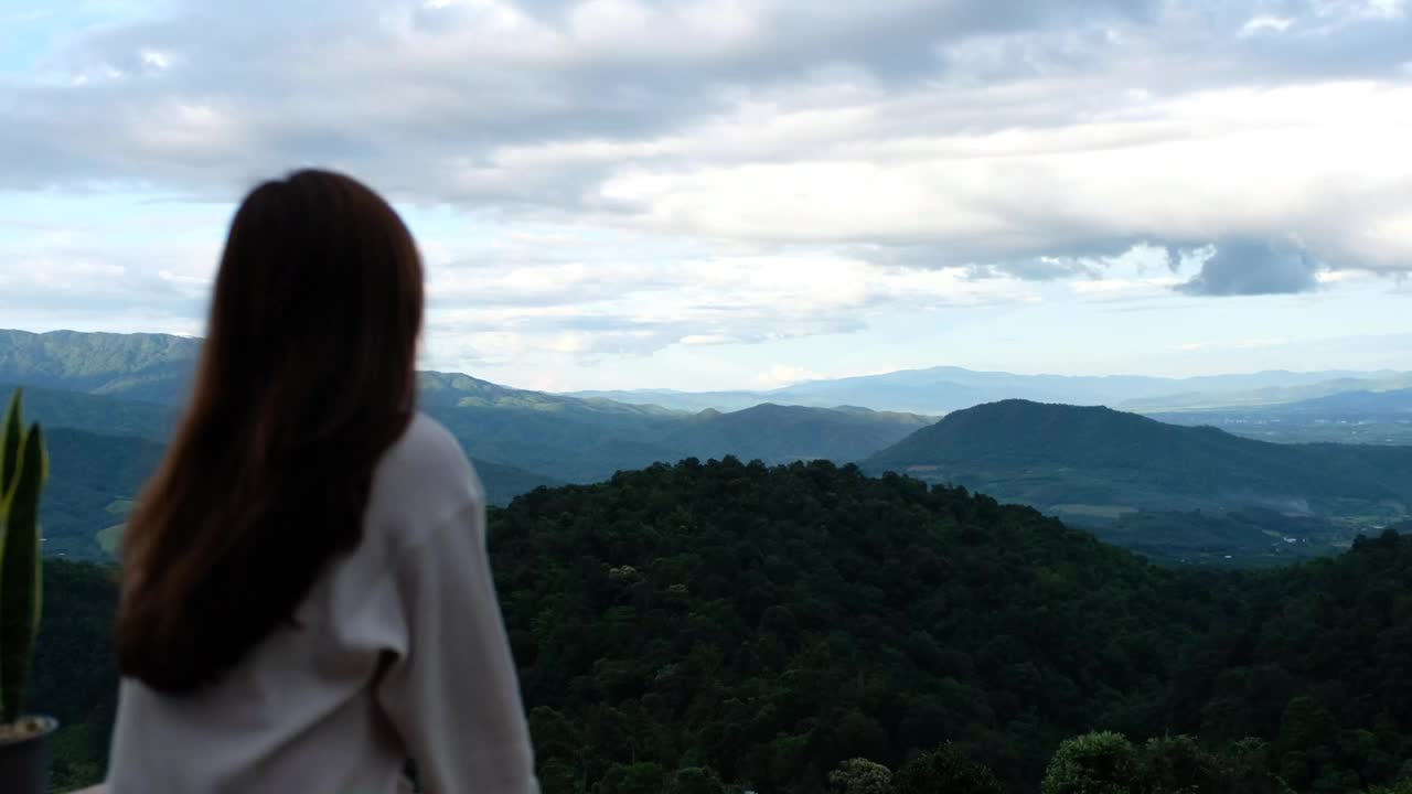 模糊的背面，一个女旅行者看一个美丽的山景视频素材