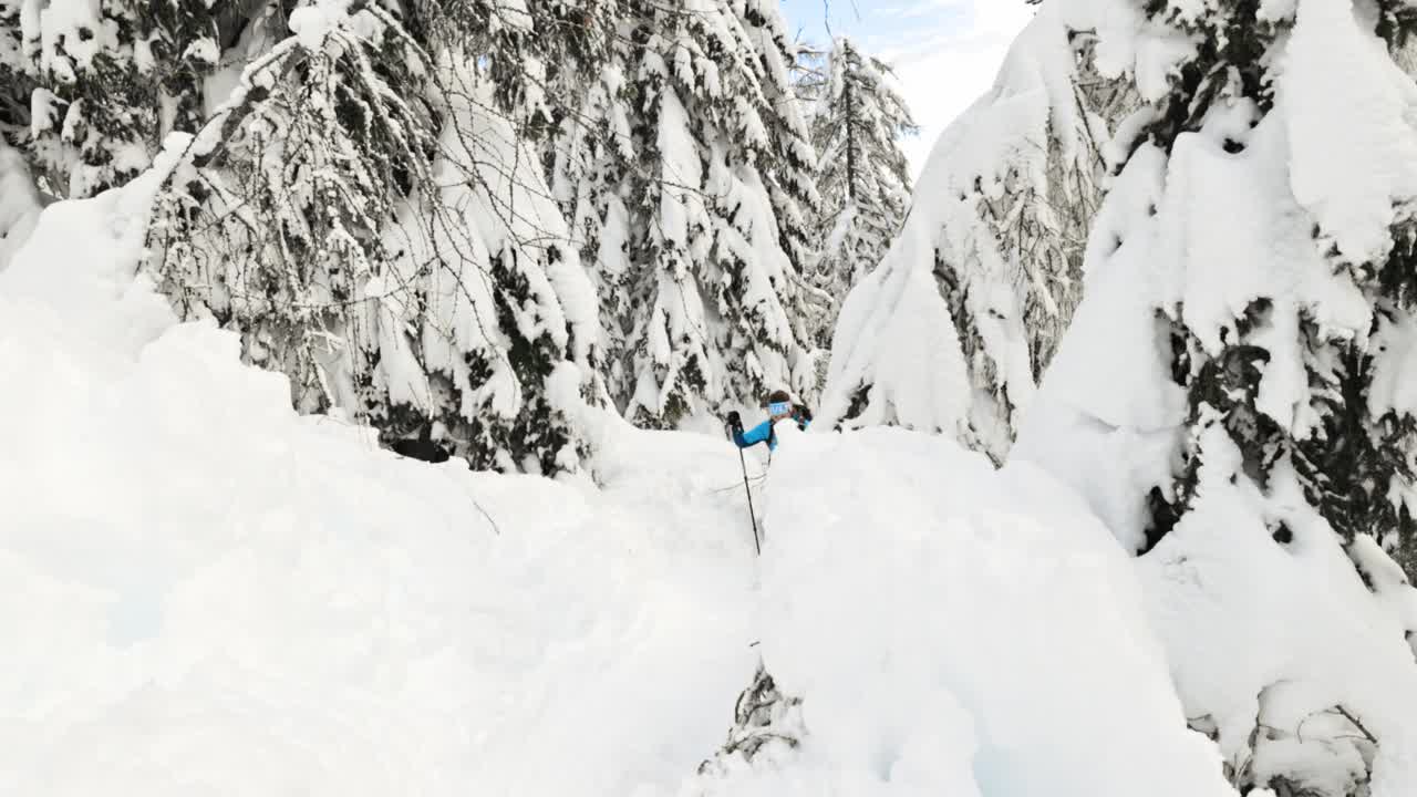 穿着蓝色夹克的徒步旅行者在狭窄的雪道上行走视频素材