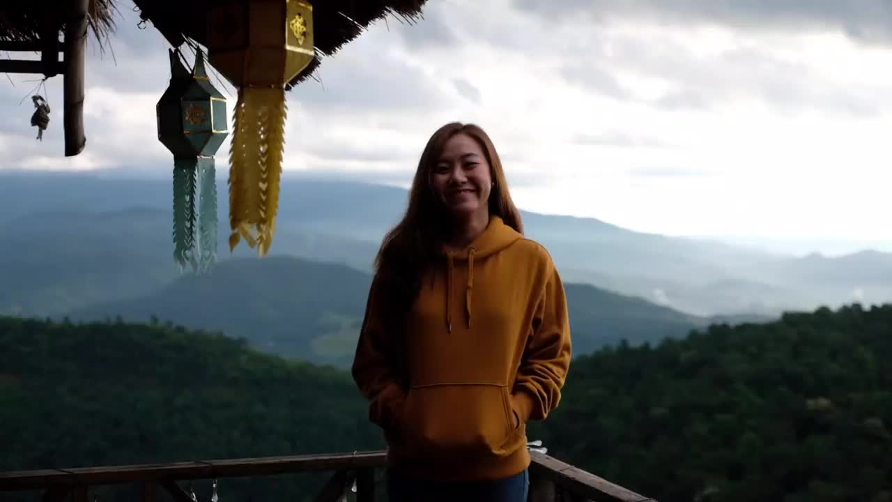 一位女游客走出木屋的慢镜头，看到了美丽的山景视频素材