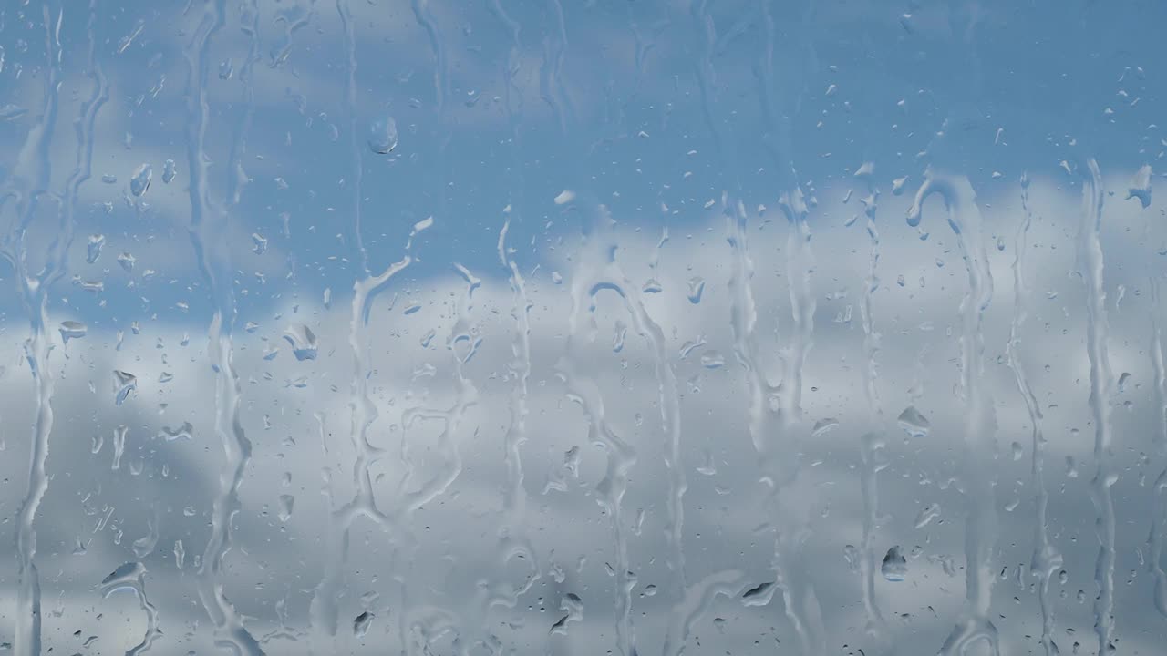 雨点落在窗户上，下雨天，蓝天和白云落在窗户玻璃旁视频素材