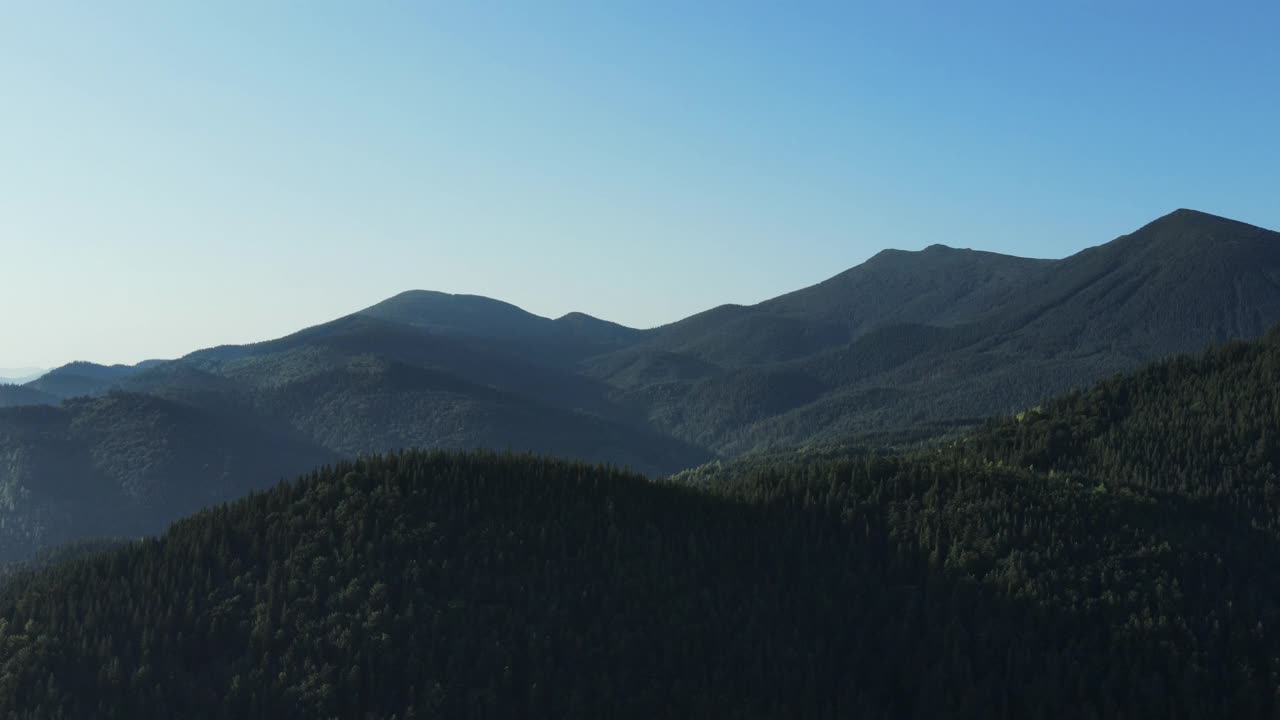 无人机拍摄飞越树梢，美丽的夏天和秋天平静的山脉在蓝色的清晨天空背景。公园探索和旅游目的地的旅游和旅游的概念视频素材