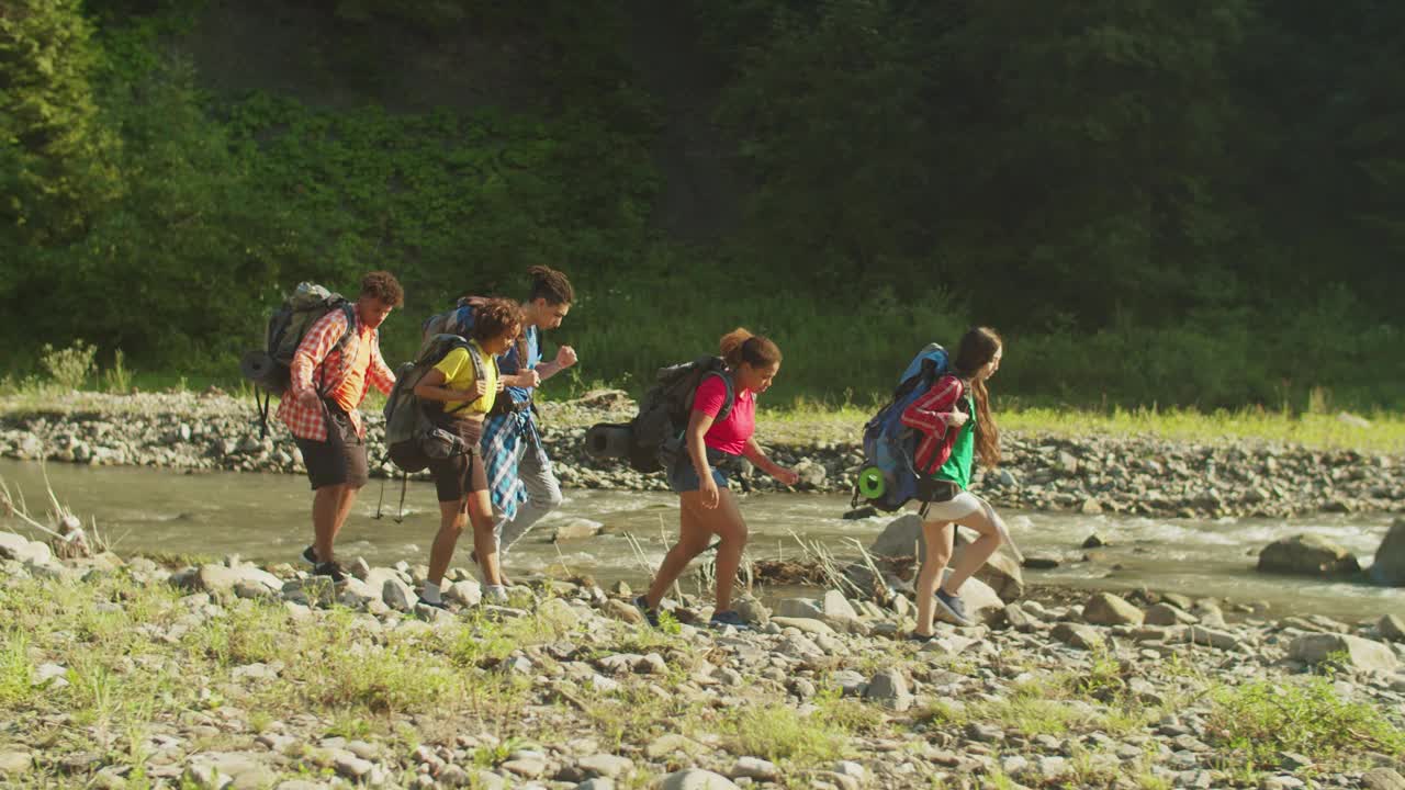 一群积极多元的多民族背包客在山河附近徒步旅行视频素材