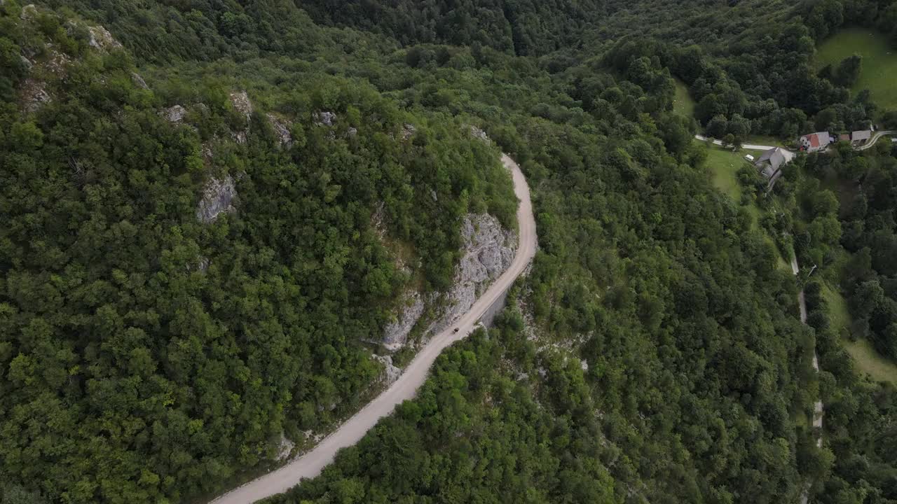 鸟瞰图上的摩托车驾驶在蜿蜒的乡村道路上的山坡视频素材