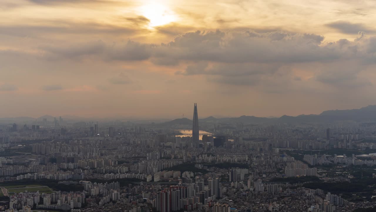 从首尔松坡区南汉山城看日落时，蚕室区乐天世界塔周围的市中心云朵从白天到晚上的景色视频素材