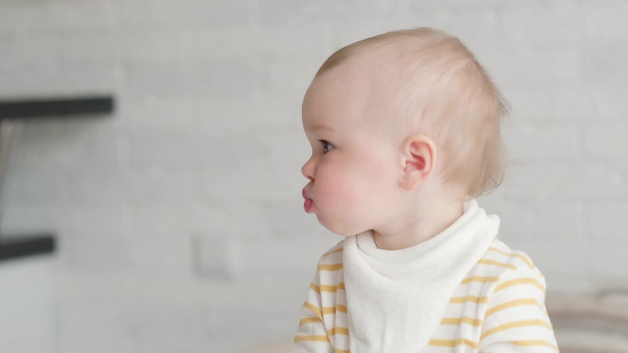 在家吃宝宝的照片。健康食品，午餐时间。孩子做鬼脸。孩子坐在桌子上，手里拿着碗视频素材