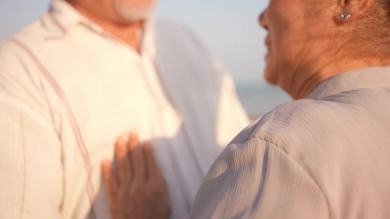 4K亚洲老年夫妇在夏日日落的海滩上享受浪漫的假期，翩翩起舞视频素材