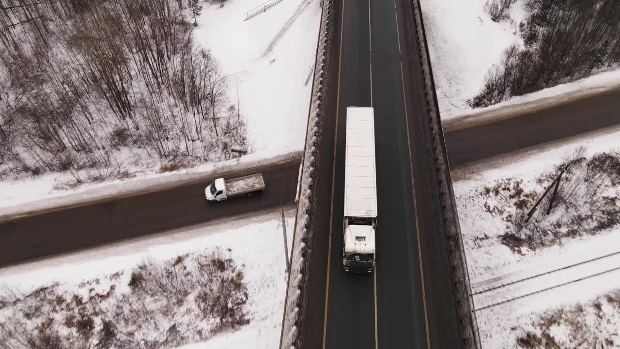 鸟瞰图:一辆大而长的卡车在冬季的一条双车道公路上行驶。视频素材