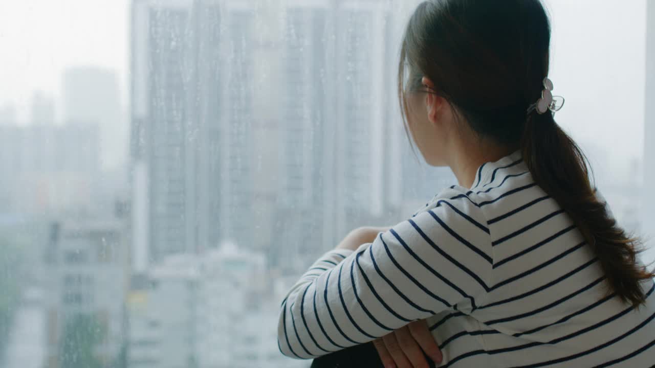 女人看着窗外的雨滴视频素材