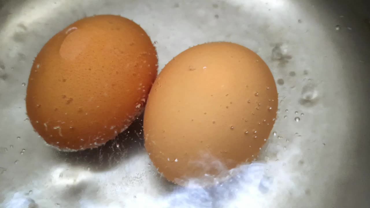 在锅里煮鸡蛋看起来就像沸水冒出的泡沫。烹饪有机鸡蛋。视频下载