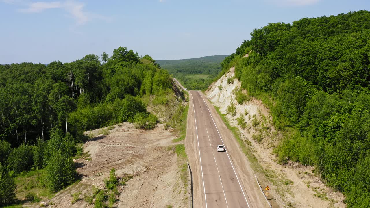 一辆白色汽车沿着乡村道路行驶的鸟瞰图视频素材