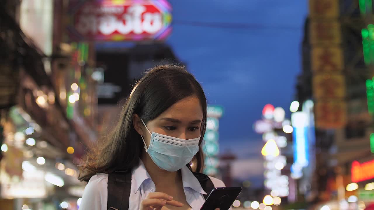 年轻的亚洲女人戴着面膜，用手机看地图视频素材