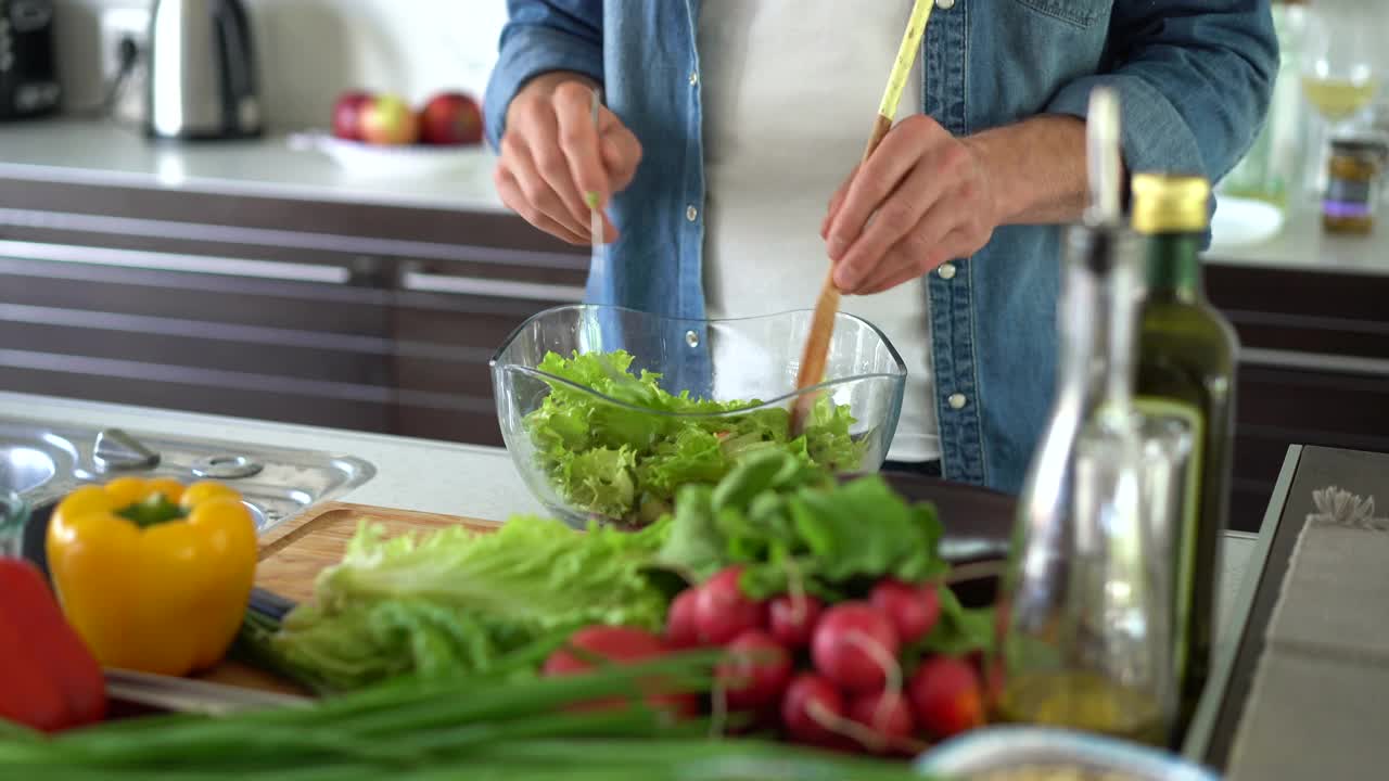 准备食物。男人做沙拉，在碗里混合材料，准备晚餐视频素材