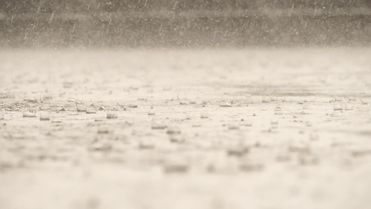 雨落在水泥地面上的水面上时，水滴形态的慢动作速度特写视频素材