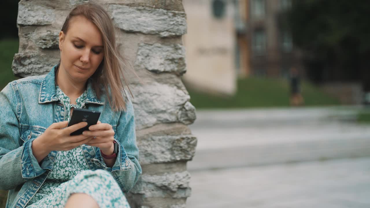 带着智能手机的女人在老城区休息。视频素材