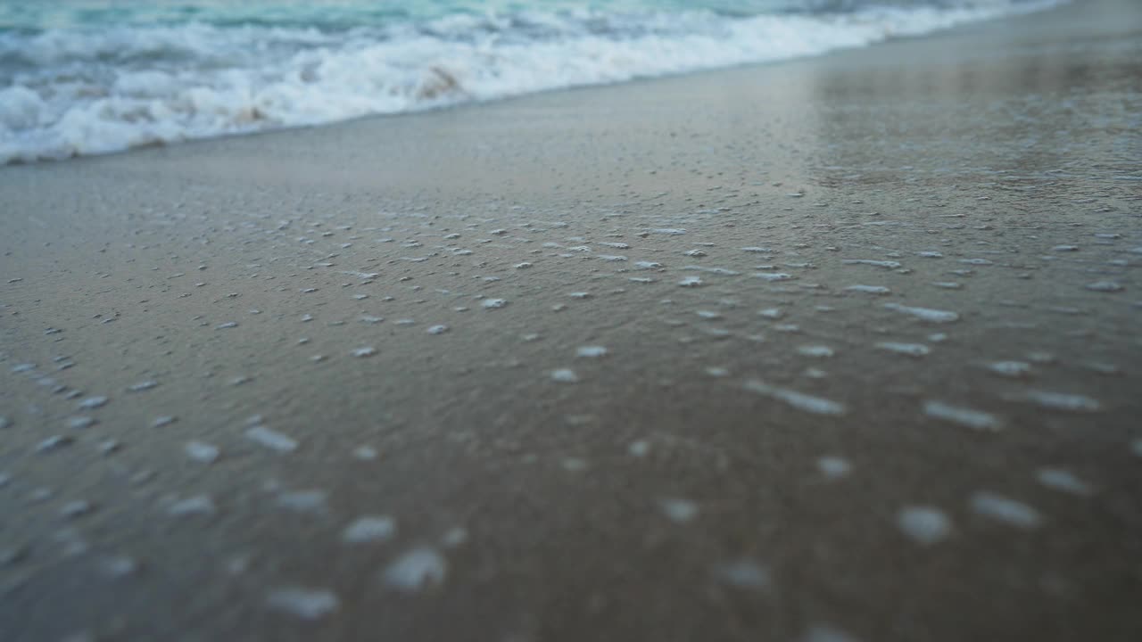 特写的蓝绿色泡沫地中海海浪翻滚在沙滩上的户外。清澈湛蓝的海水溅在海边的沙滩上。住相机。视频素材