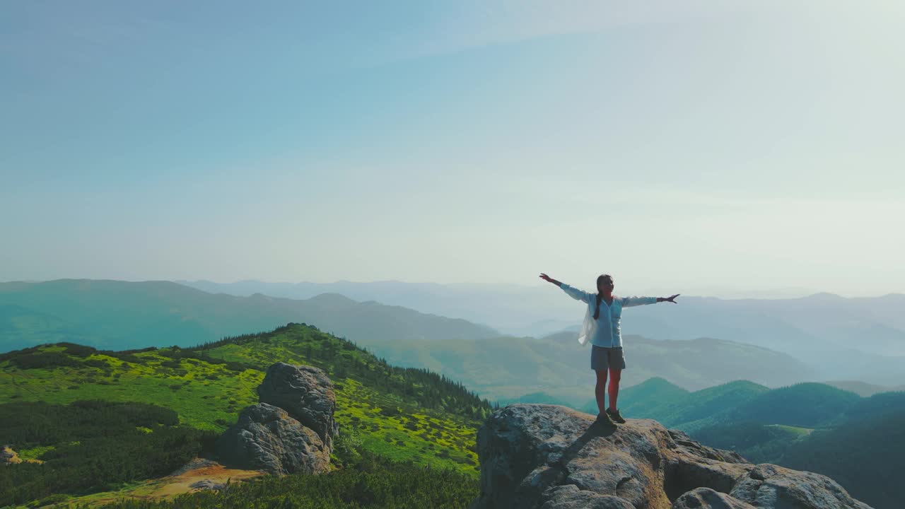 快乐的女人站在大石头上。乌克兰喀尔巴阡山脉的美丽风景。清晨在山上。女游客站着旋转视频素材