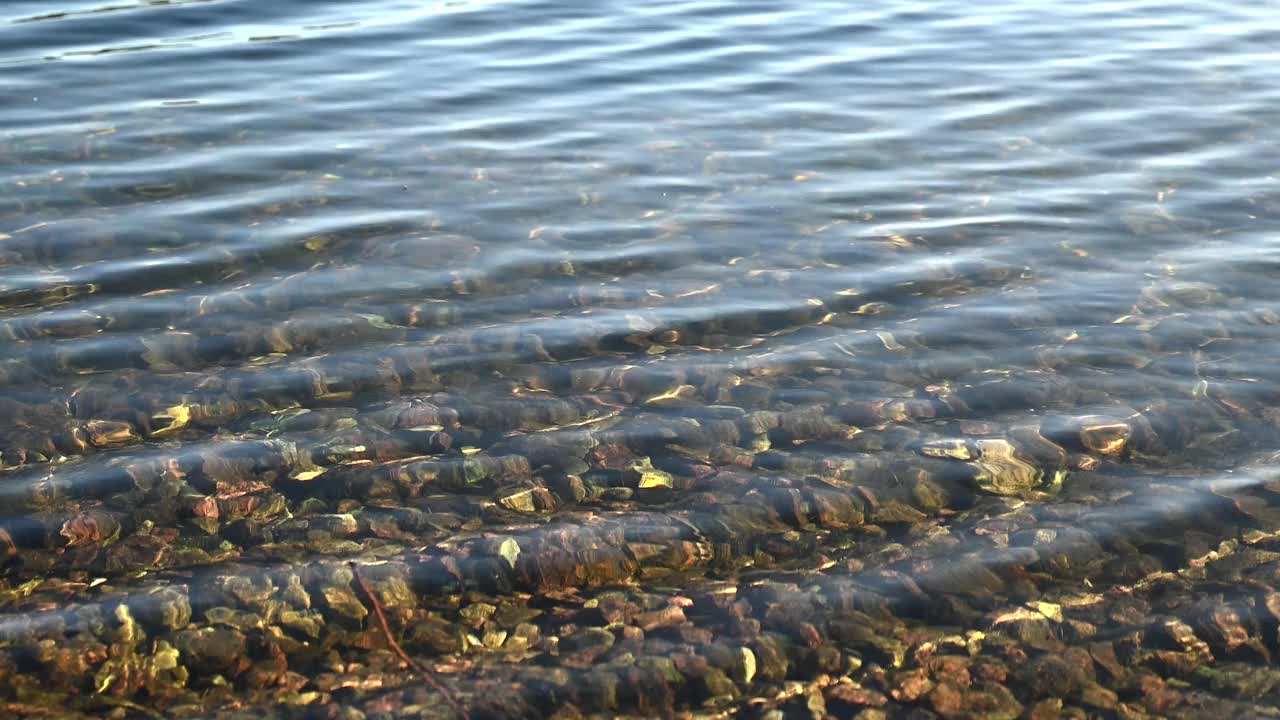 透明的湖面泛起涟漪，湖底有小卵石视频素材