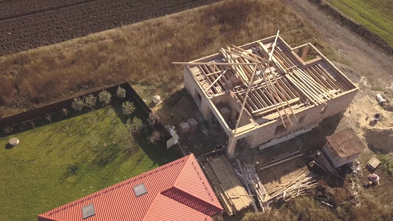 从上往下鸟瞰两幢私人住宅，一幢是在建的木结构屋顶，另一幢是红瓦屋顶。视频素材