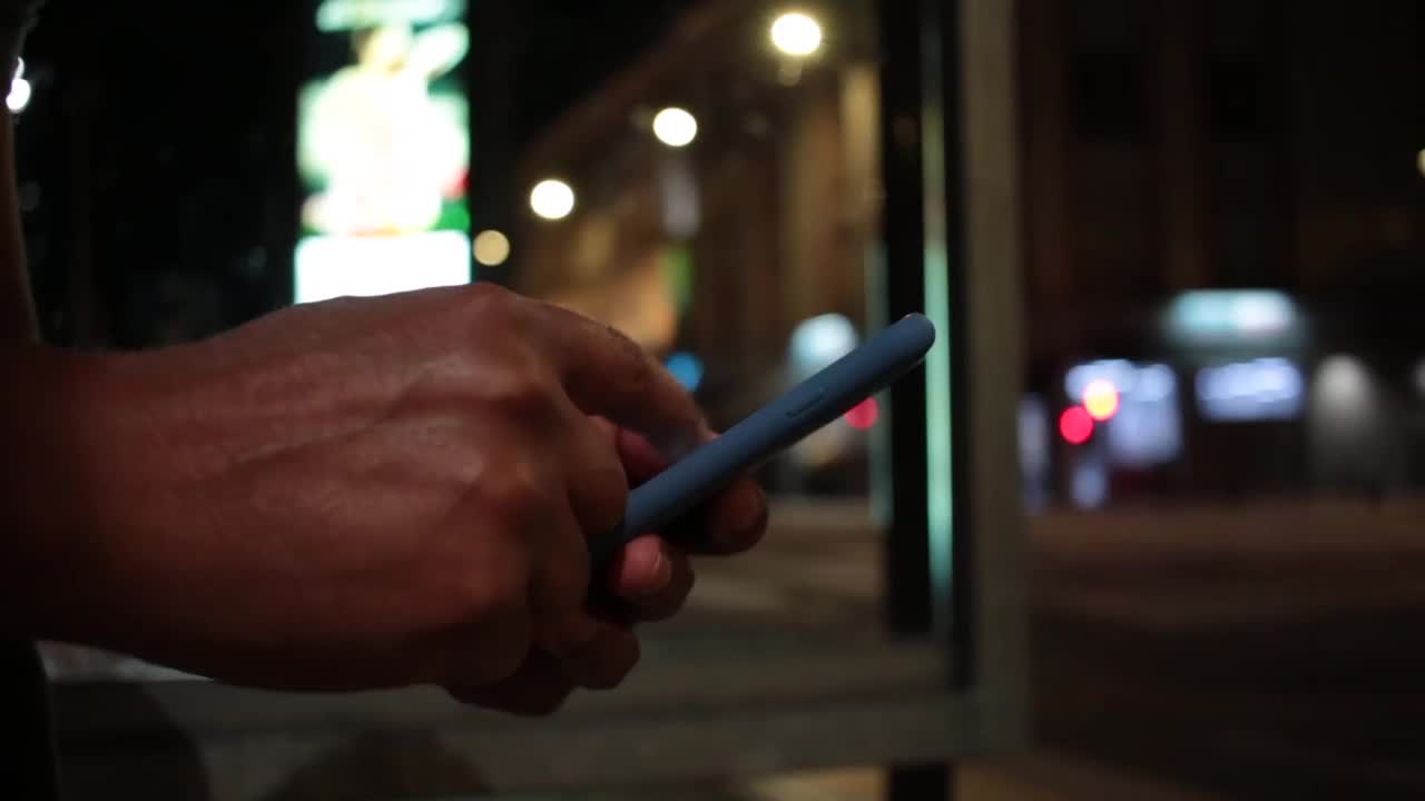 夜晚，非洲年轻人在城市的人行道上看手机视频素材