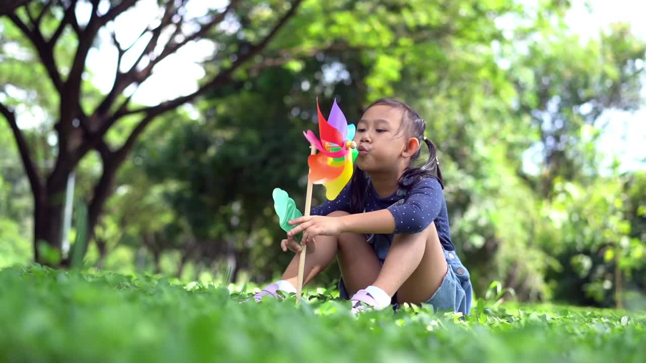 快乐的亚洲小女孩在花园里玩纸风车视频下载