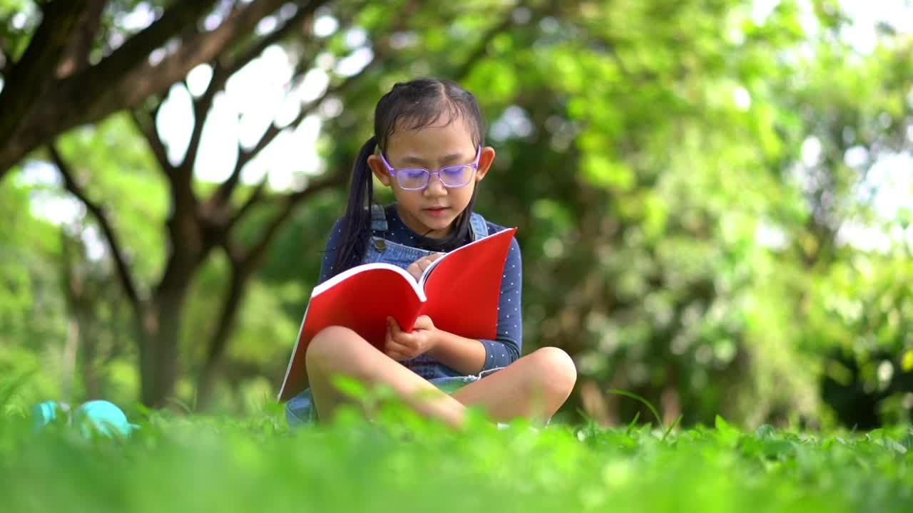 快乐的亚洲小女孩在花园里看书视频下载