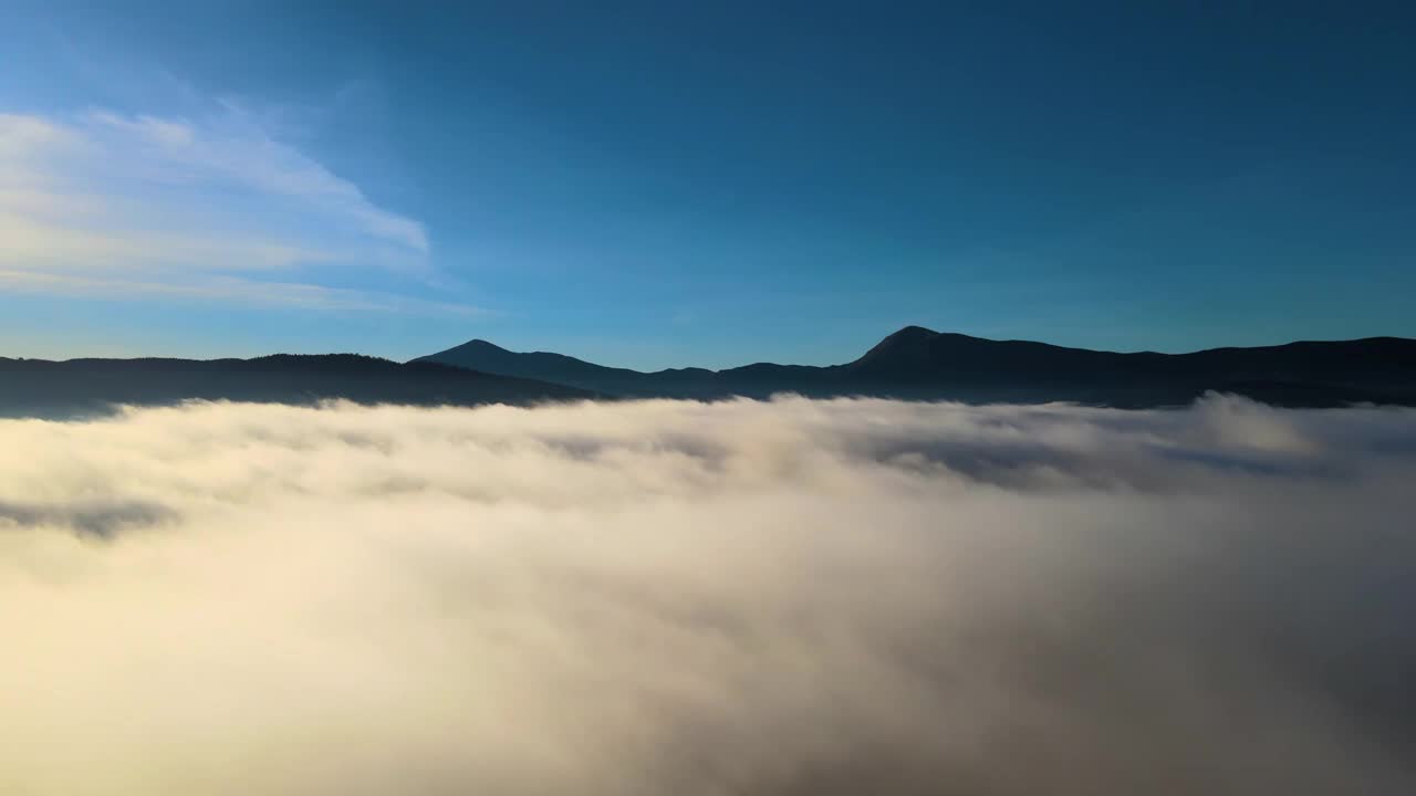 鸟瞰图的景观在雾蒙蒙的快速移动的云覆盖山在日落。视频素材