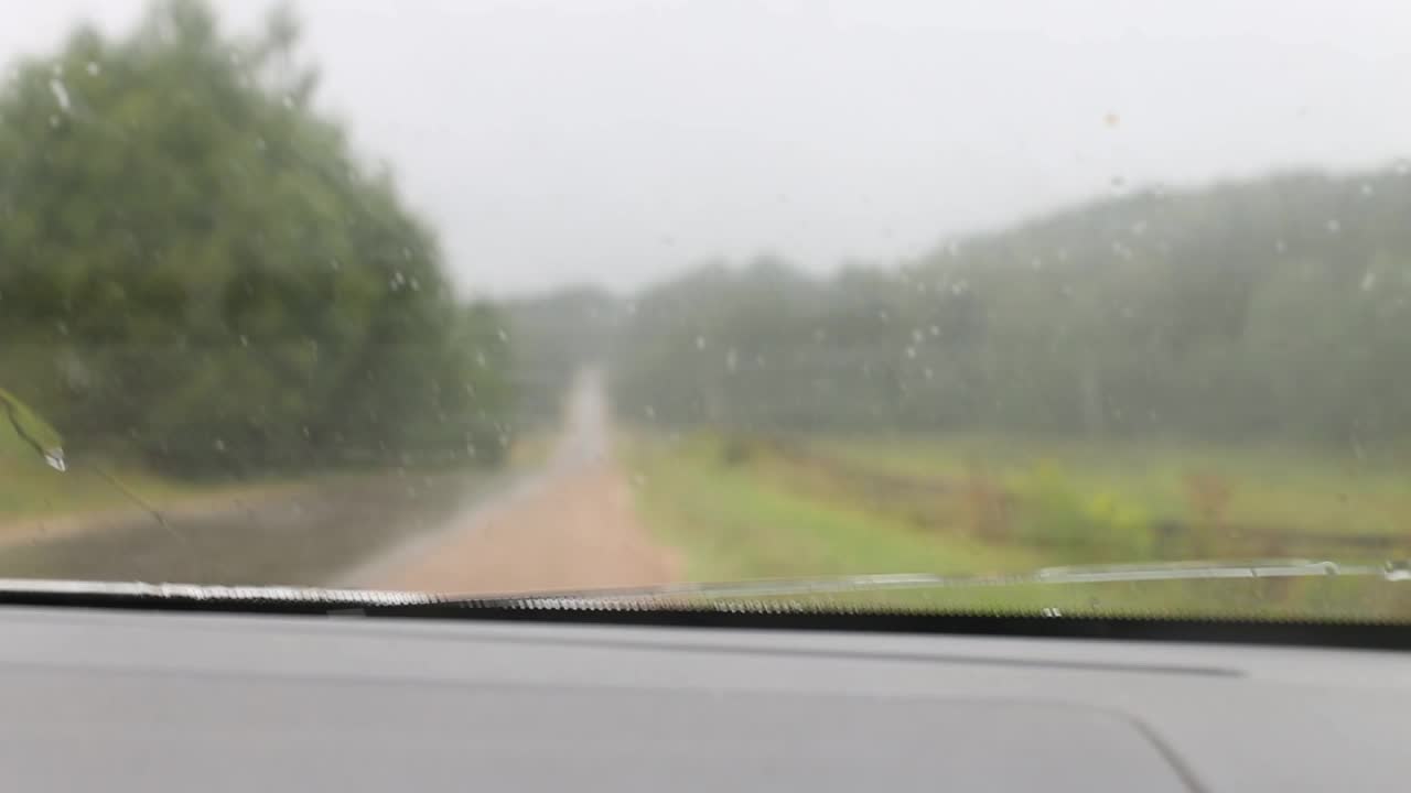 雨天透过车窗看路。挡风玻璃的雨刷可以冲走雨滴。软焦点视频素材