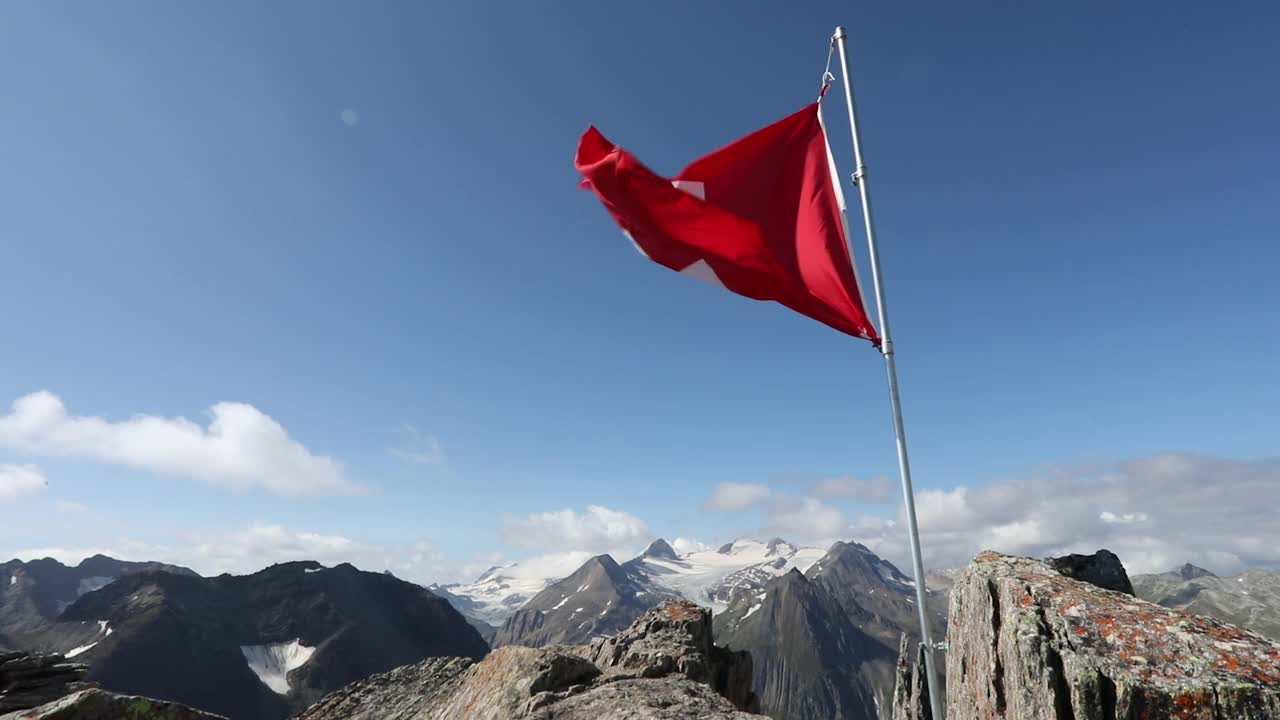 瑞士国旗从山顶上飘扬的风景视频素材